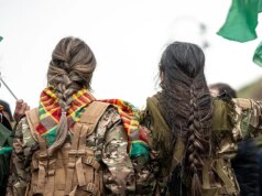 Miliciano sírio mostra o que afirma ser a trança cortada de um combatente curdo enquanto Damasco assume o controle